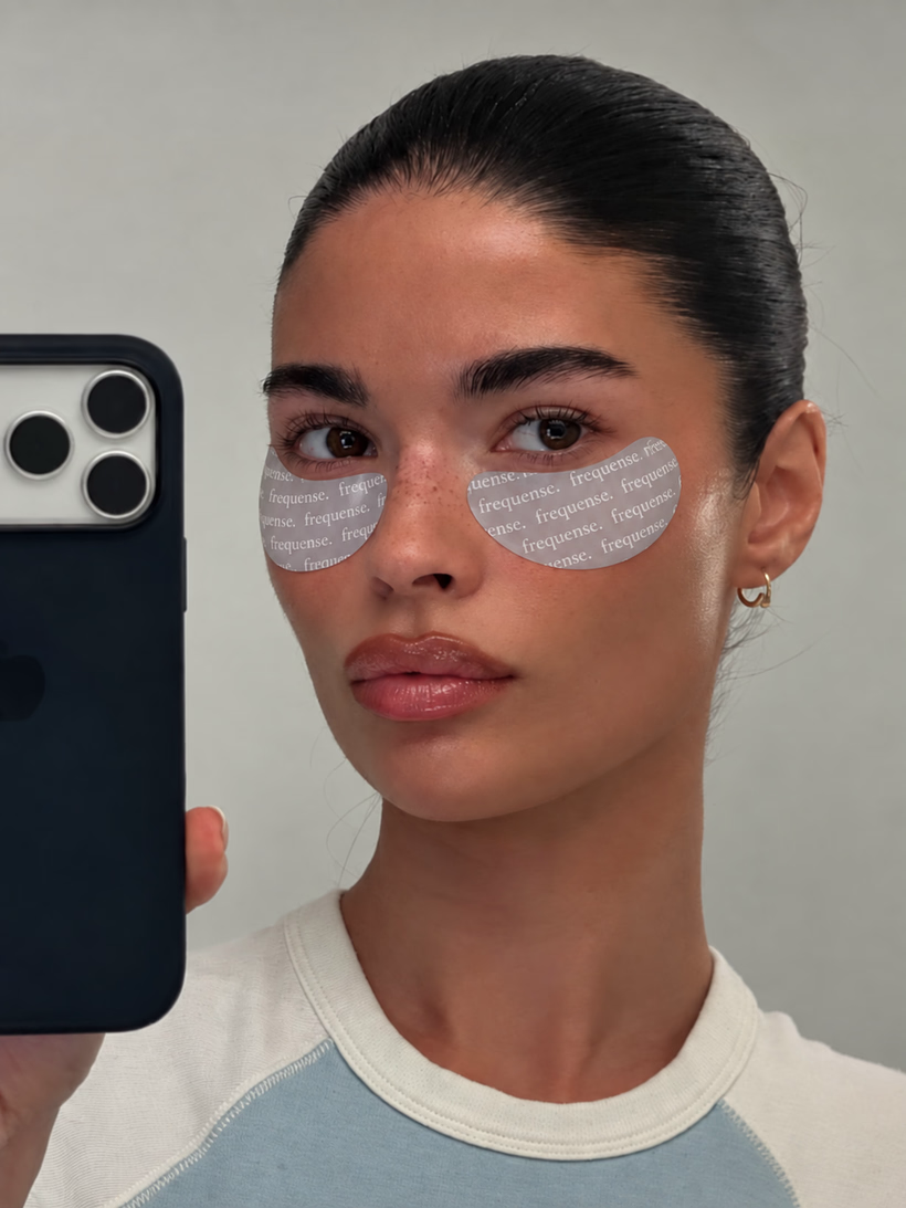 Woman wearing Frequense Peptide Eye Masks, taking a mirror selfie